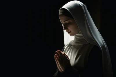 Young Nun Praying With Clasped Hands In Dark Setting