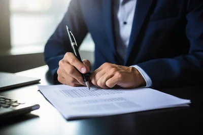 Businessman Signing Important Documents At Office Desk
