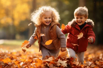 Happy Children Playing With Autumn Leaves In Park
