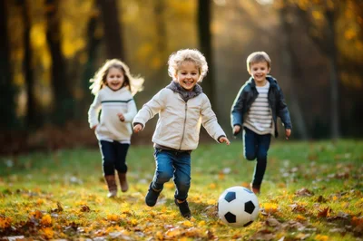 Three Happy Children Playing Soccer in Autumn Park