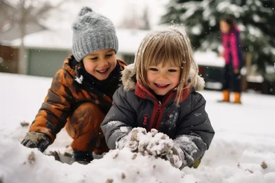 Two Young Children Playing Together In The Snow