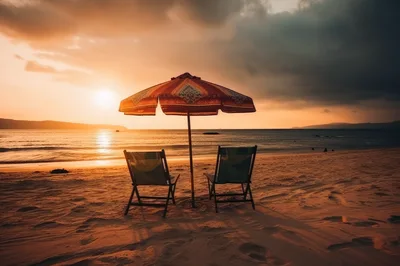 Two Empty Beach Chairs Under Umbrella At Sunset