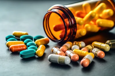 Assorted Pharmaceutical Capsules Spilled From Amber Bottle