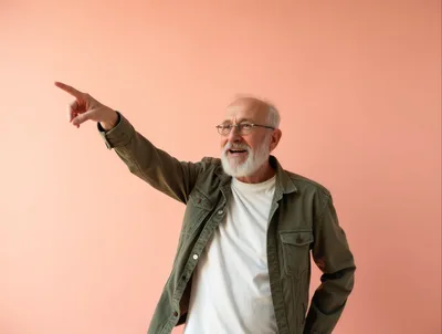 Senior Man Pointing Away Against Peach Background