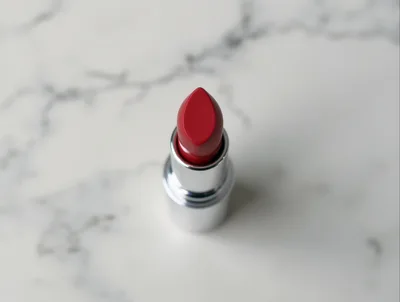 Red Lipstick Tube Standing On White Marble Surface