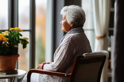 Elderly Woman Sitting By Window Looking Outside