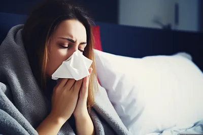 Sick Woman Blowing Her Nose In Bed