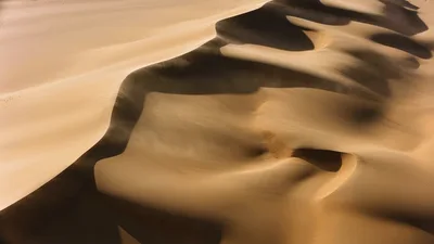 Aerial View Of Wind Sweeping Across Desert Sand Dunes