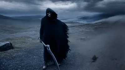 Grim Reaper Standing In A Misty Barren Landscape