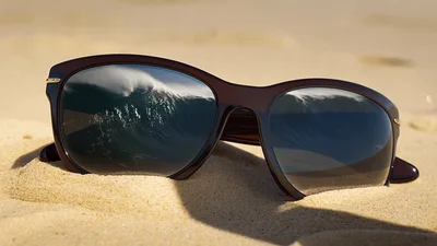 Sunglasses Resting On Sandy Beach With Ocean Reflection