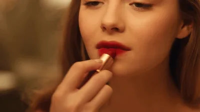 Young Woman Applying Vibrant Red Lipstick In Mirror