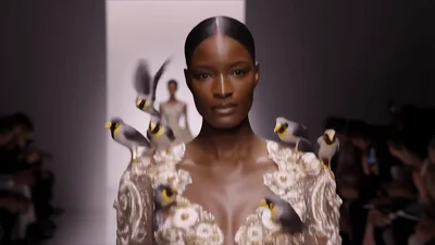 Model Walking Down Runway With Digital Birds Flying Around