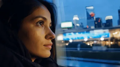 Young Woman Looking Out Train Window At Cityscape