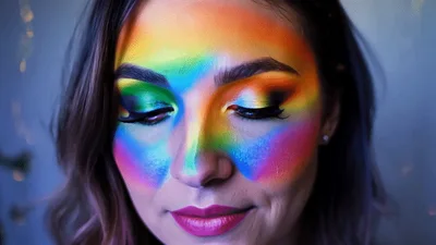 Woman With Artistic Rainbow Makeup Looking At Camera