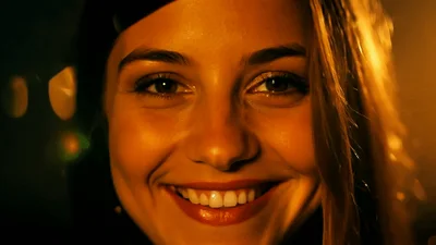Young Woman Smiling Warmly Under Golden Night Lighting