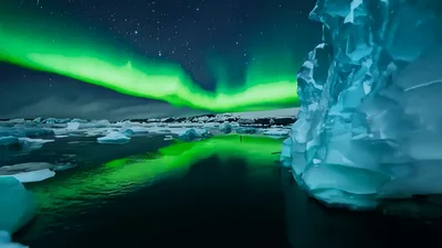 Aurora Borealis Shimmering Over Arctic Icebergs In Still Water