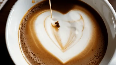 Barista Pouring Steamed Milk Into Coffee Cup