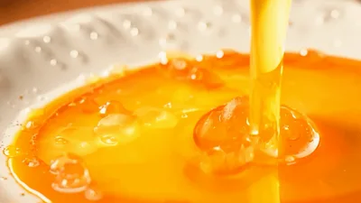 Golden Honey Pouring Onto A White Plate