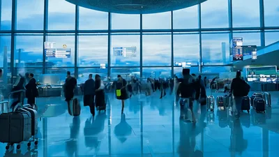 Busy Airport Terminal With Passengers Walking During Sunset