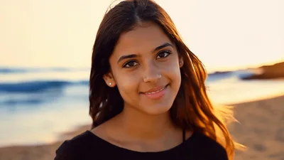Young Woman Smiling And Waving On A Sunny Beach