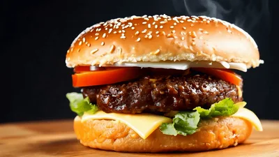 Hand Pressing Down On A Fresh Gourmet Cheeseburger