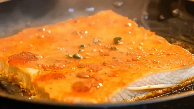 Seasoning A Piece Of Fish In A Frying Pan