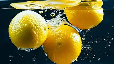 Three Fresh Lemons Dropping Into Clear Water