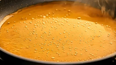 Pouring Dark Liquid Into Hot Oil In Frying Pan