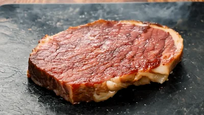 Grilled Ribeye Steak Resting On A Black Plate