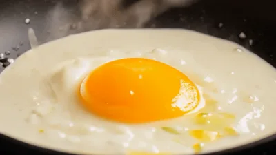 Raw Egg Dropped Into Hot Frying Pan