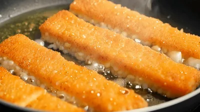 Golden Breaded Fish Sticks Frying In A Pan