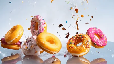Assorted Glazed Donuts Falling Onto Reflective Surface