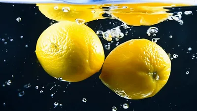 Two Fresh Lemons Falling Into Water