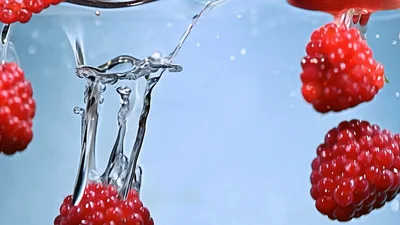 Fresh Raspberries Falling Into Clear Water With Bubbles