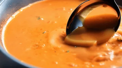 Ladle Stirring Creamy Tomato Soup In A Bowl