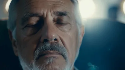 Elderly Man Sitting In A Dark Office Looking Thoughtful