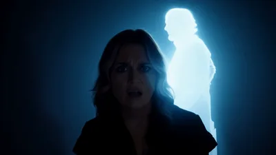Terrified Woman Reacting To Glowing Ghostly Figure Behind Her