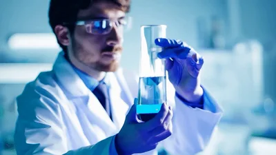Scientist Examining Blue Chemical Solution In Laboratory