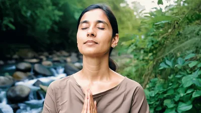 Woman Meditating With Hands In Prayer Position Outdoors