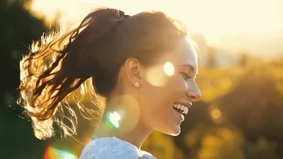 Happy Young Woman Laughing Outdoors In Golden Hour Sunlight