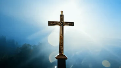 Golden Christian Cross Standing Against A Misty Morning Sky