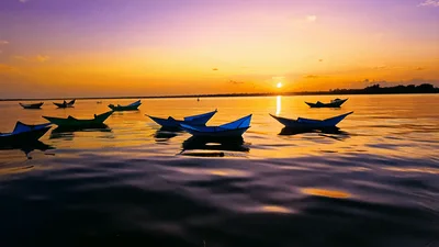 Colorful Paper Boats Floating On Calm Lake At Sunset