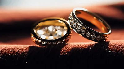 Two Elegant Gold Wedding Rings Resting On Textured Fabric