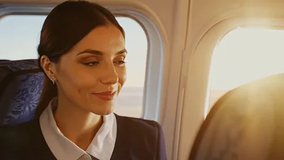Flight Attendant Smiling While Sitting In Airplane Cabin