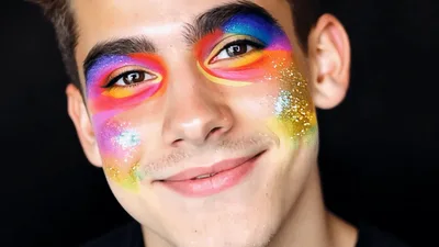 Young Man With Artistic Rainbow Makeup Smiling At Camera