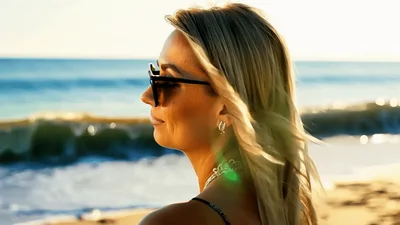 Blonde Woman Adjusting Sunglasses On A Sunny Beach