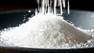 White Rice Grains Pouring Into A Black Bowl