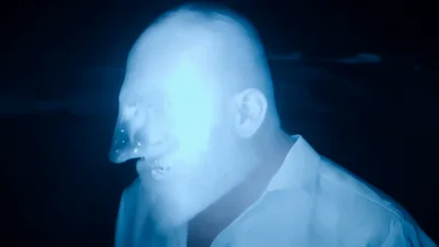 Man With Glowing Blue Face In Dark Setting