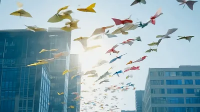 Colorful Mechanical Birds Flying Between Modern City Buildings