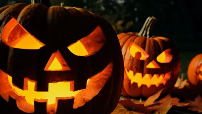 Glowing Jack O Lanterns Sitting On Autumn Leaves